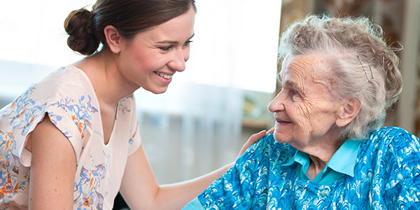 Caregiver sharing tea with elderly man in kitchen